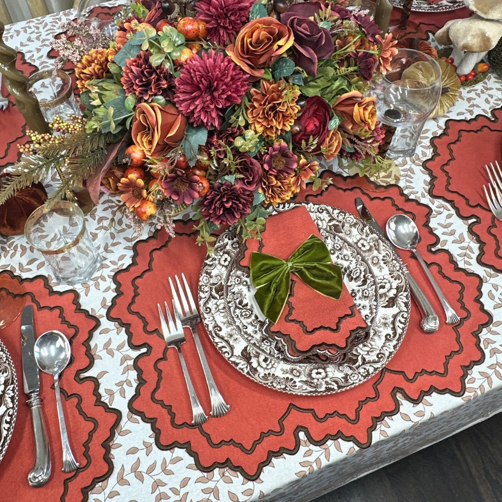 Fall Table Linens Woodland leaves tablecloth and napkin with leather Charlotte placemat and olive napkin bow- Woodland Spode china fall table linens Decorative table setting with floral centerpiece, pumpkin placemats, and silverware on a leaves tablecloth.