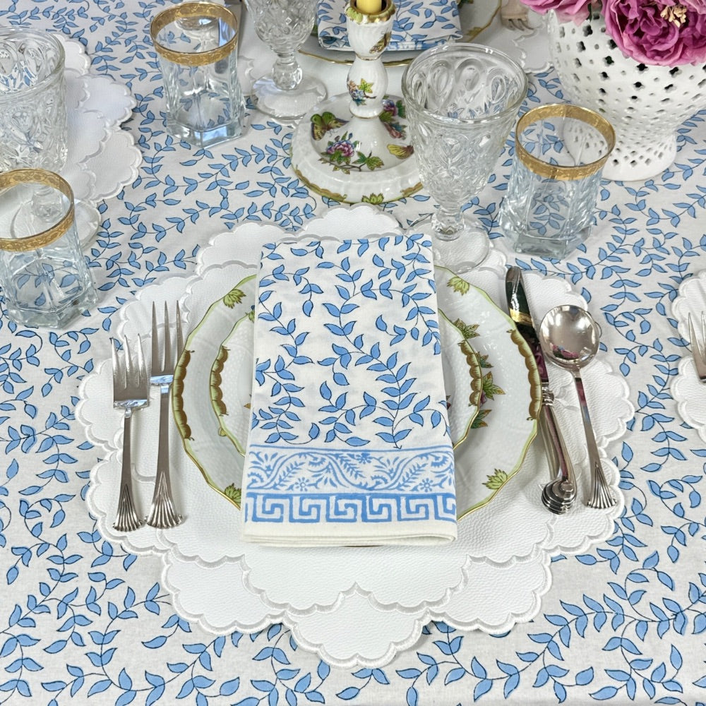 White vegan leather placemat with white embroidery on blue leaves tablecloth with matching napkin 