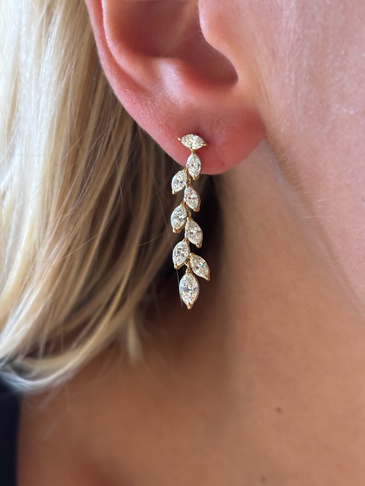 Close-up of a woman's ear wearing Marquise Diamond Waterfall Drop Earrings, featuring a gold leaf-inspired design with marquise and brilliant cut diamonds arranged in a cascading pattern.