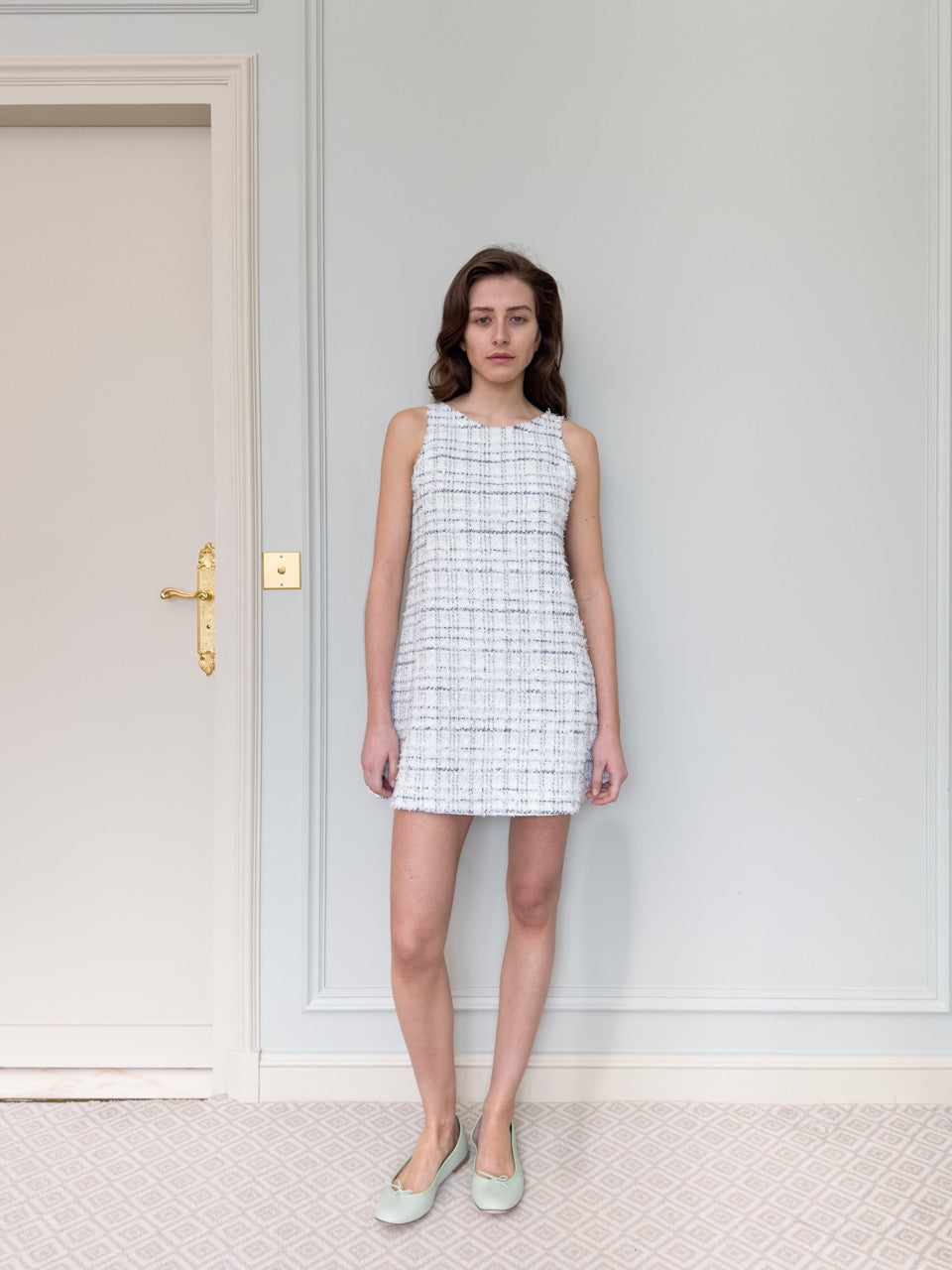 Front view of Jane Dress in Azur, a sleeveless tweed mini with raw edges against a pale gray wall