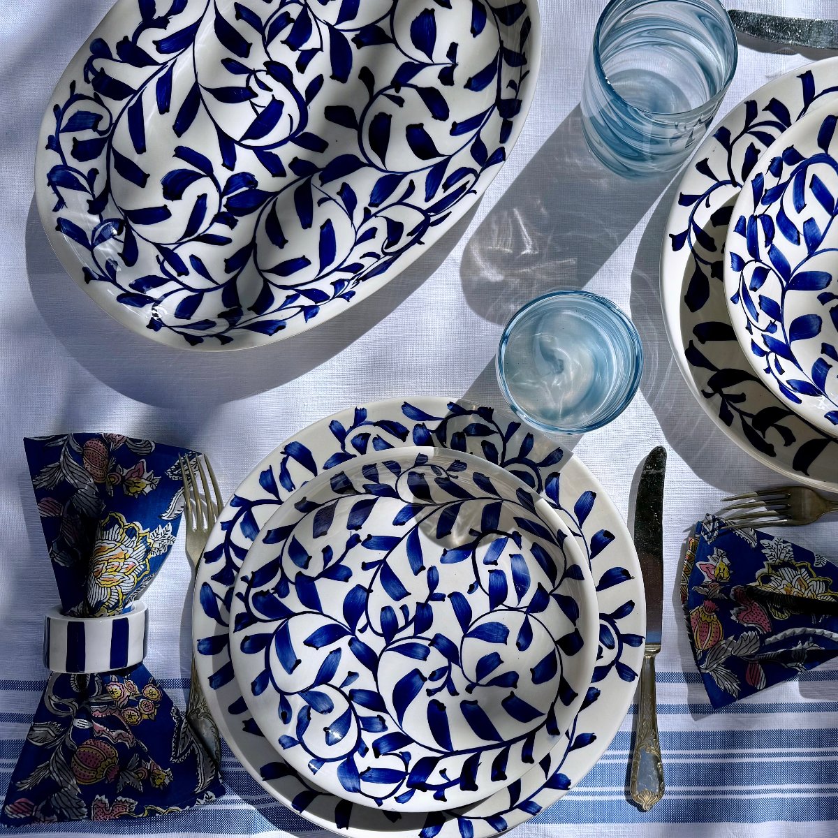 Overhead view of Navy Blue Scroll Dinner Set, 16-Piece showcasing hand-painted navy scroll motif on blue-and-white table setting