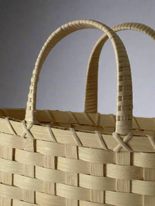 Close-up of a woven basket with a handle on a plain background