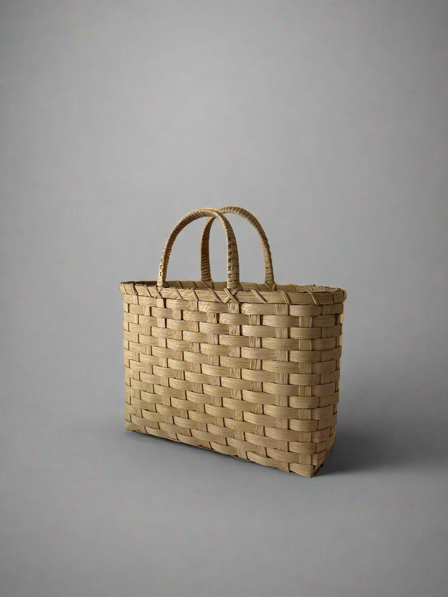Woven basket with handles on a plain background