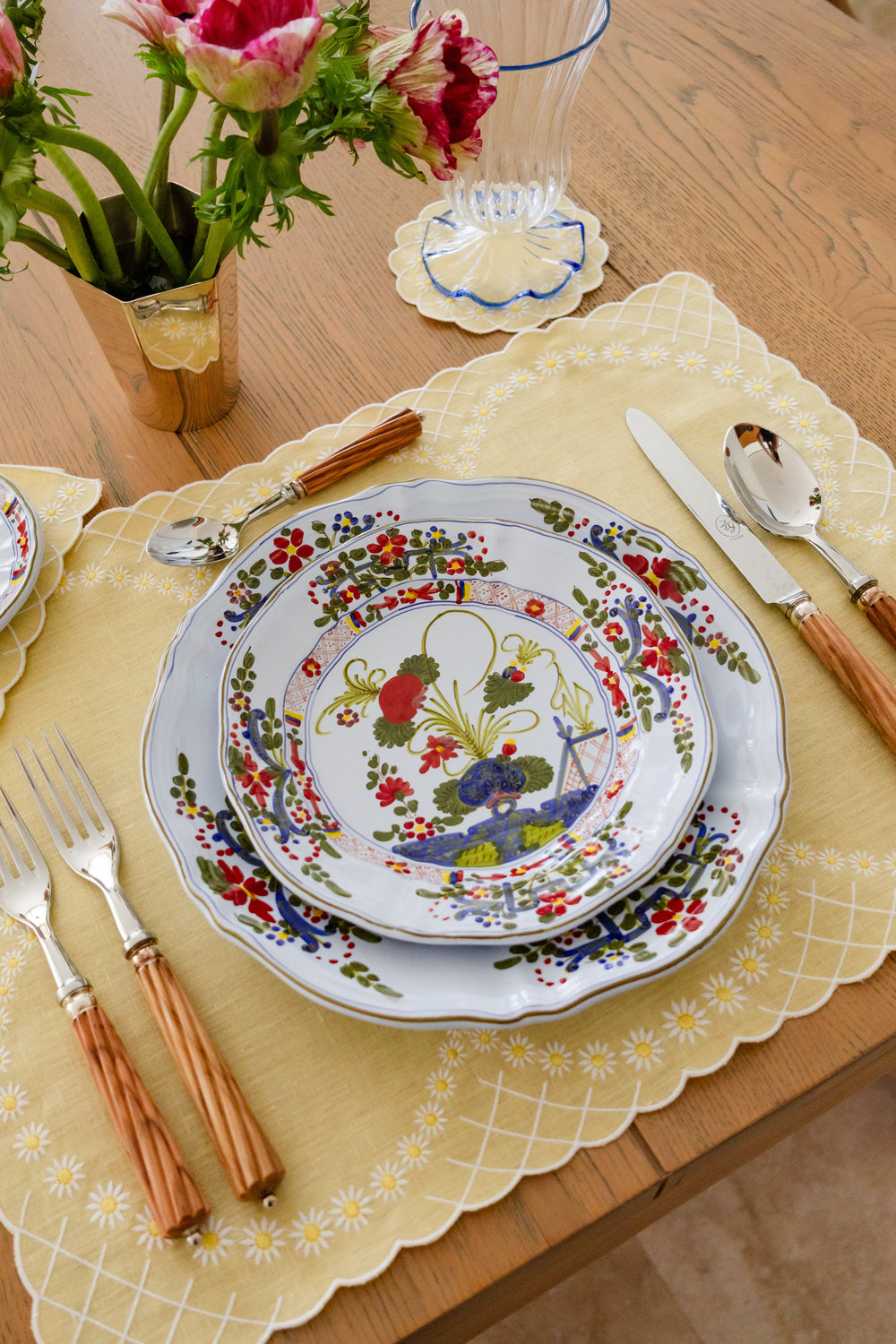 Top-down view of yellow Daisy linen placemat showing white embroidered daisies and scalloped edge on a wooden table with plates and cutlery
