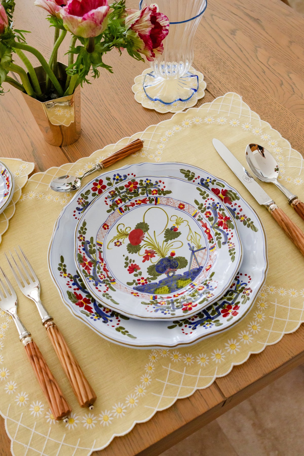 Top-down view of yellow Daisy linen placemat showing white embroidered daisies and scalloped edge on a wooden table with plates and cutlery
