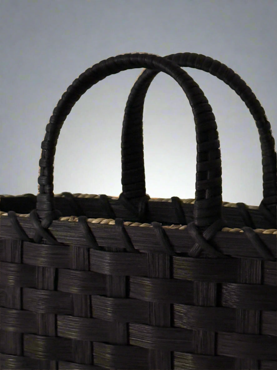 Close-up of a woven basket with black handle on a beige background