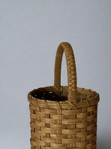 Woven basket with a handle on a plain background