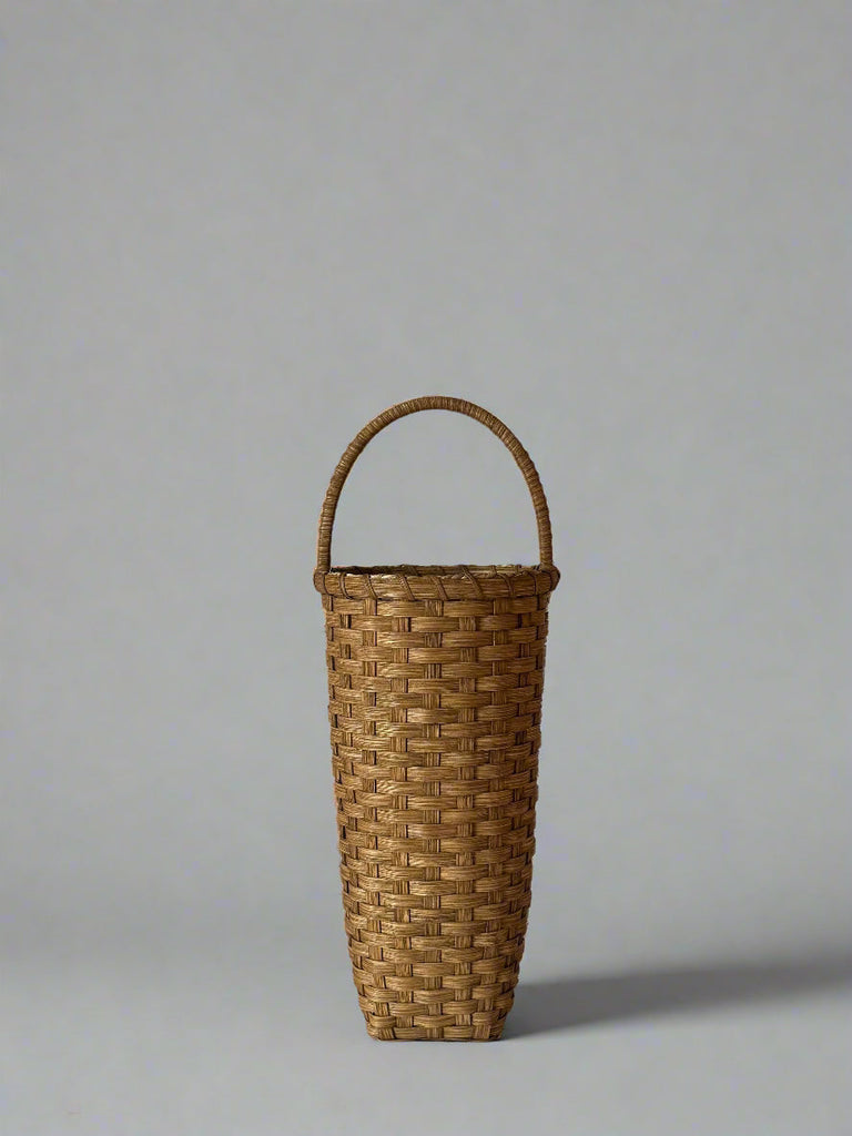 Woven basket with a handle on a plain background