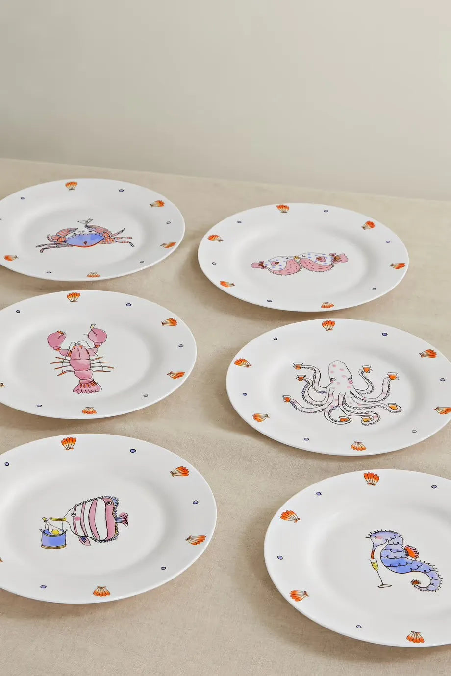 Top view of six Sea Creature Series porcelain dessert plates with playful marine illustrations and orange scallop accents
