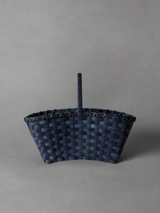 Woven basket with a handle on a light gray background