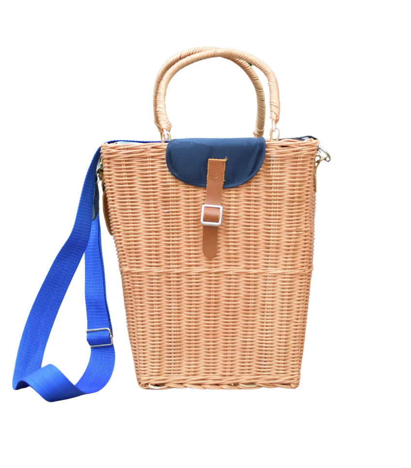 Front view of rattan picnic basket showcasing navy fabric flap, bright blue shoulder strap, and woven handles on white background
