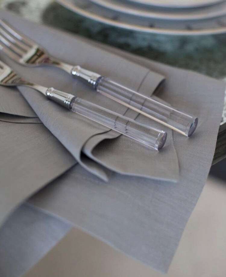 Close-up of Doric Place Setting in Crystal, Set of 5 showcasing transparent crystal-inspired acrylic handles on gray napkins
