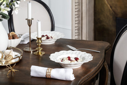 Angled top view of Royal Classic deep plate showcasing embossed seasonal motifs and gently sloped sides on a dark wood dining table