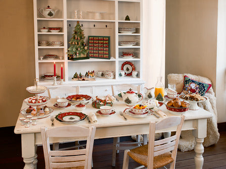 Holiday table set with Toys Delight white porcelain saucers and coffee cups, matching plates and festive decorations on a white dining table
