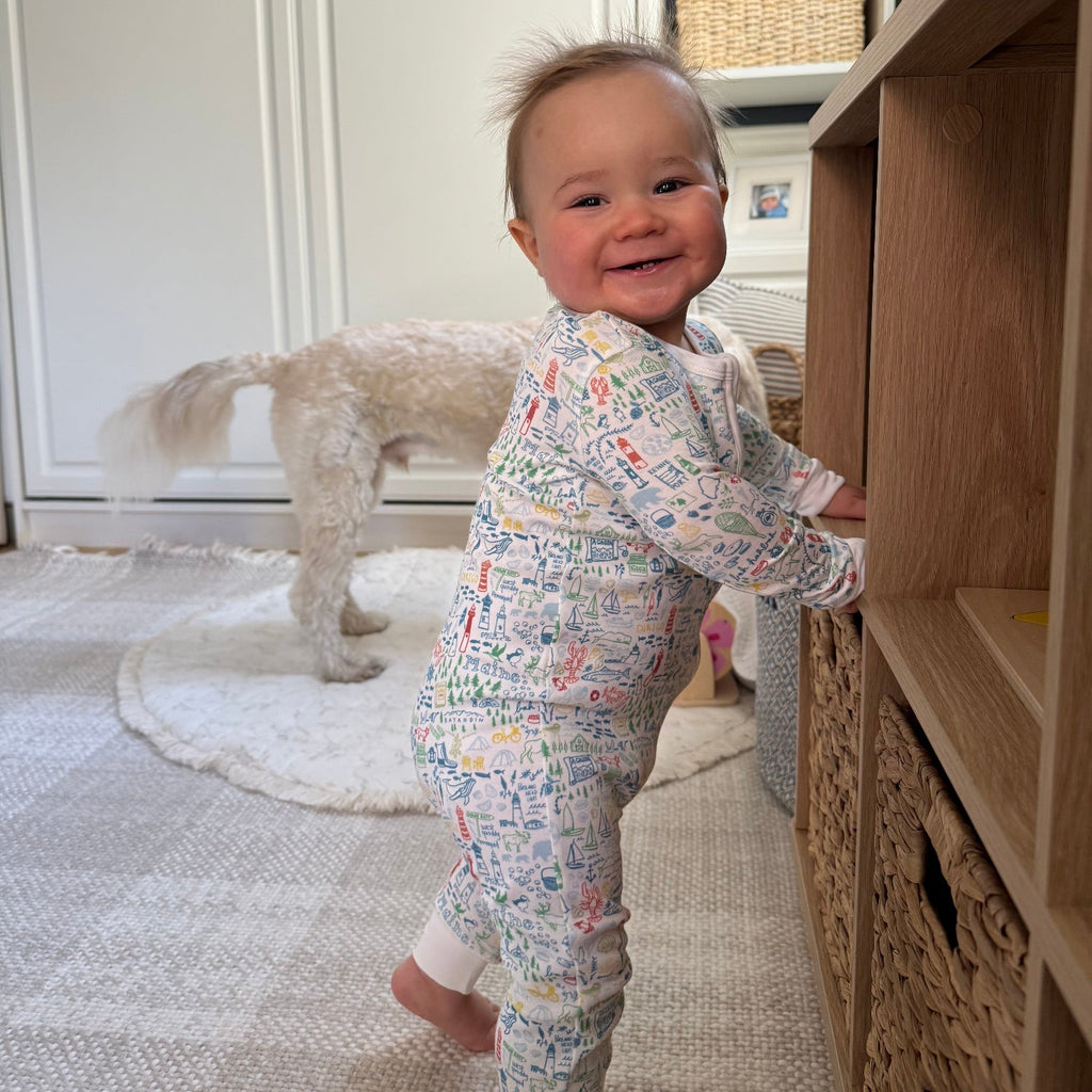 Side view of Maine Zip Baby Onesie showcasing its hand-drawn Maine landmark print on a baby indoors