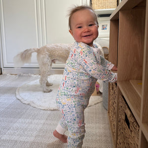 Side view of Maine Zip Baby Onesie showcasing its hand-drawn Maine landmark print on a baby indoors