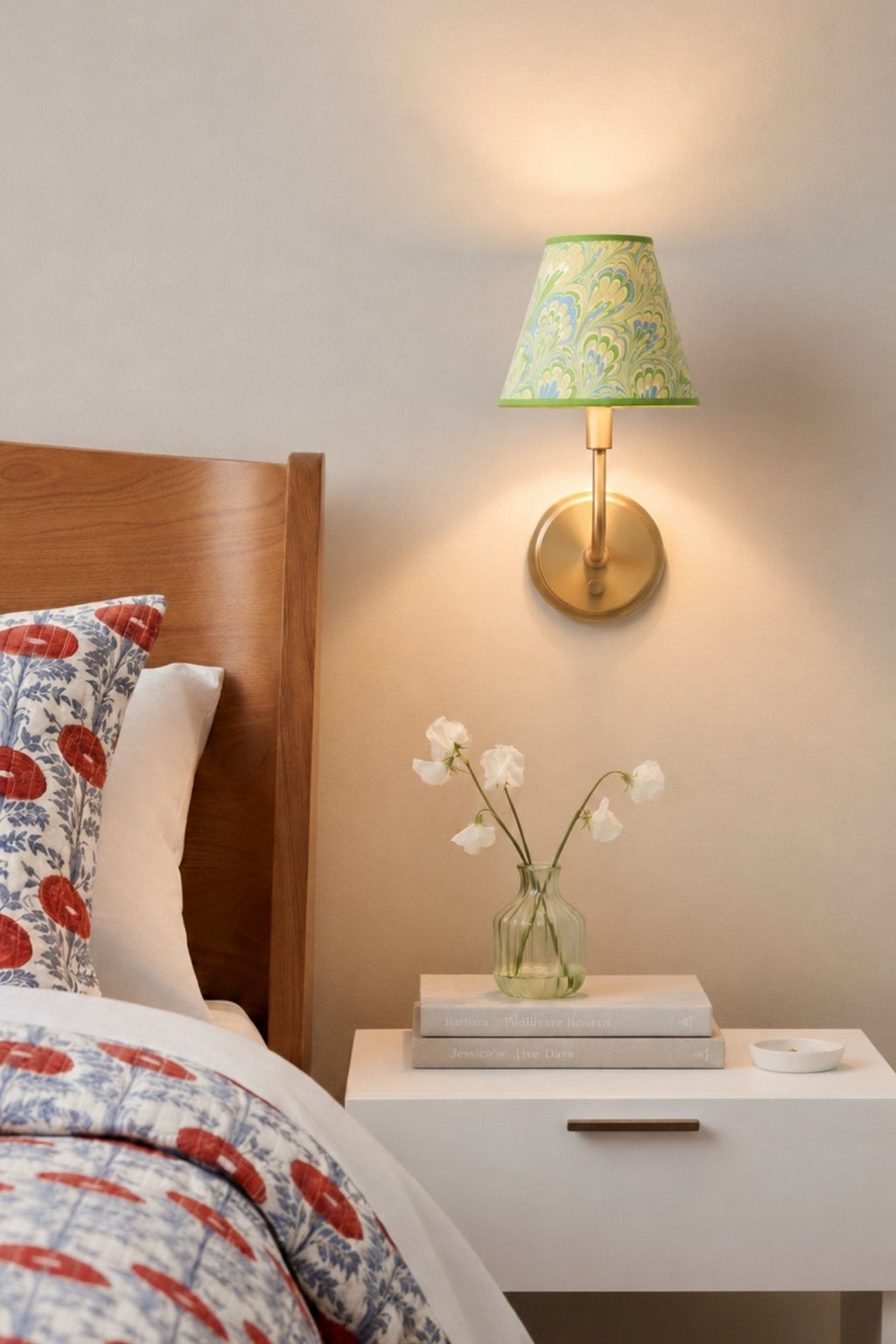 Seaglass peacock sconce illuminated on wall over nightstand
