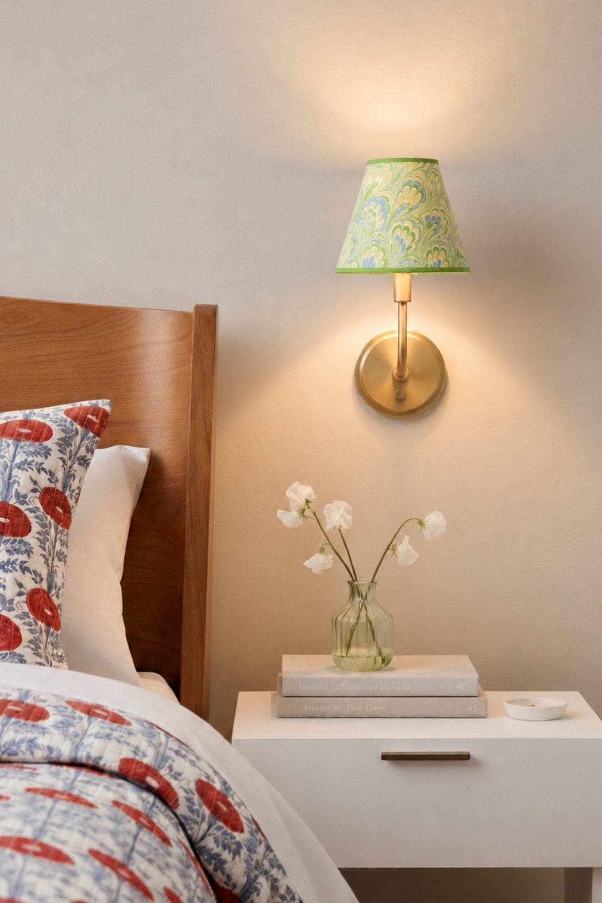 Seaglass peacock sconce illuminated on wall over nightstand