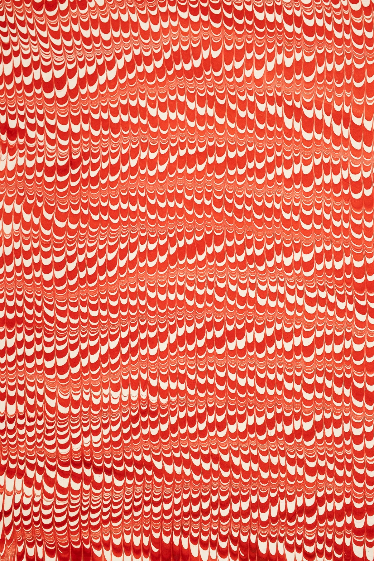 Red and white hand marbled candy cane swirl gift wrapping paper sheet close-up