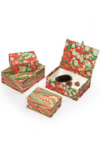 Hand-marbled keepsake box set in Christmas gems pattern with red, green, and white swirls, including open boxes with pinecones and small decorative items.