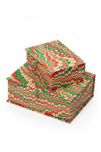 Inner Child hand-marbled keepsake box set in holiday jingle - stacked rectangular boxes with vibrant red, green, and gold marbling patterns