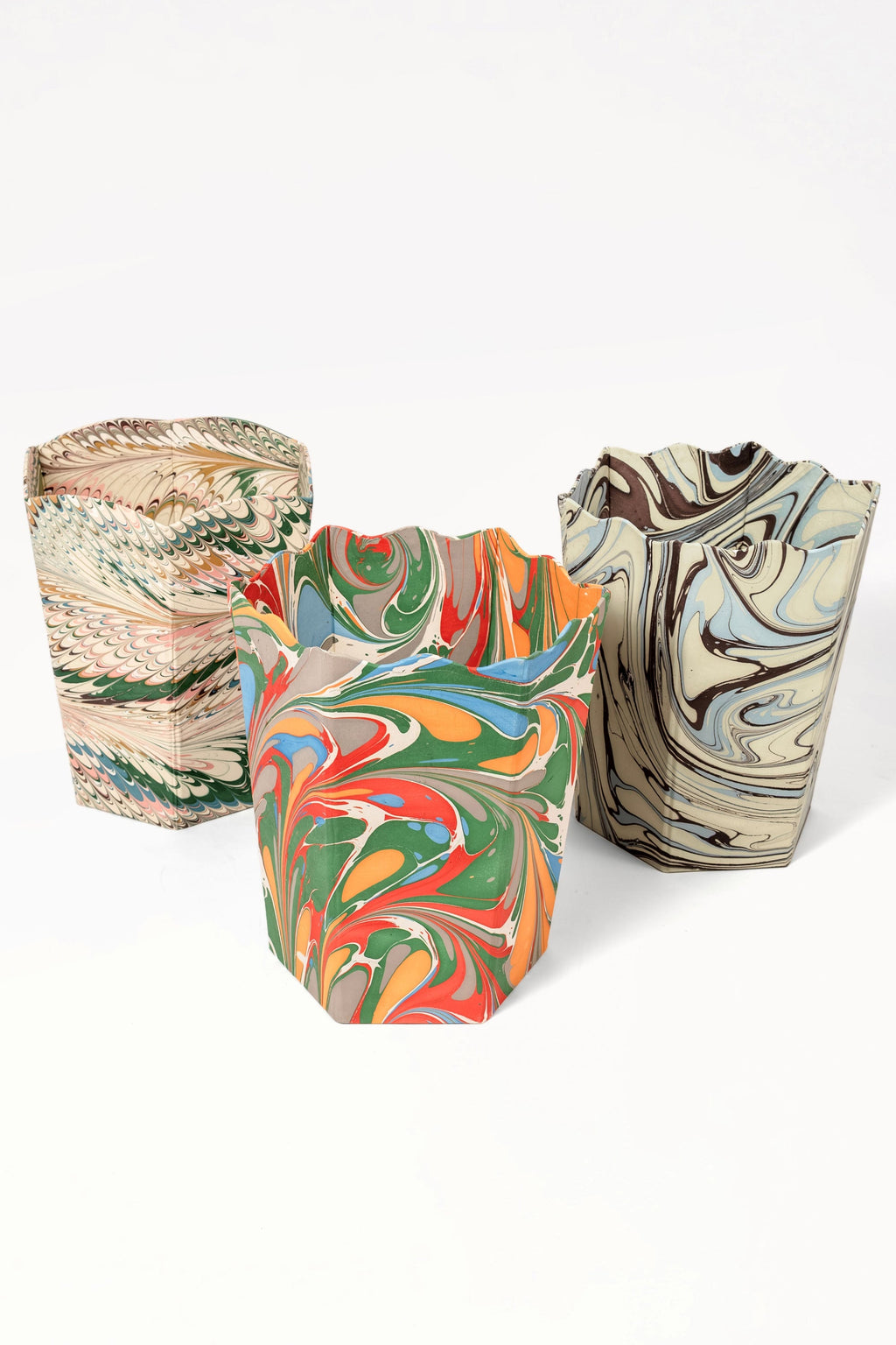 Group of hand-marbled scallop waste bins with diverse marbling patterns