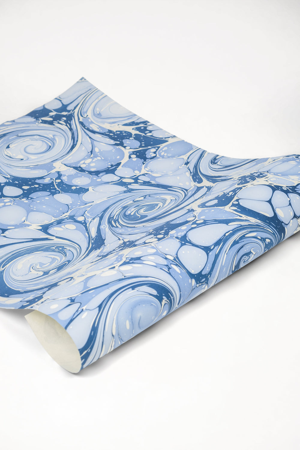 Close-up of hand-marbled blue ocean wave gift wrapping paper with swirling patterns