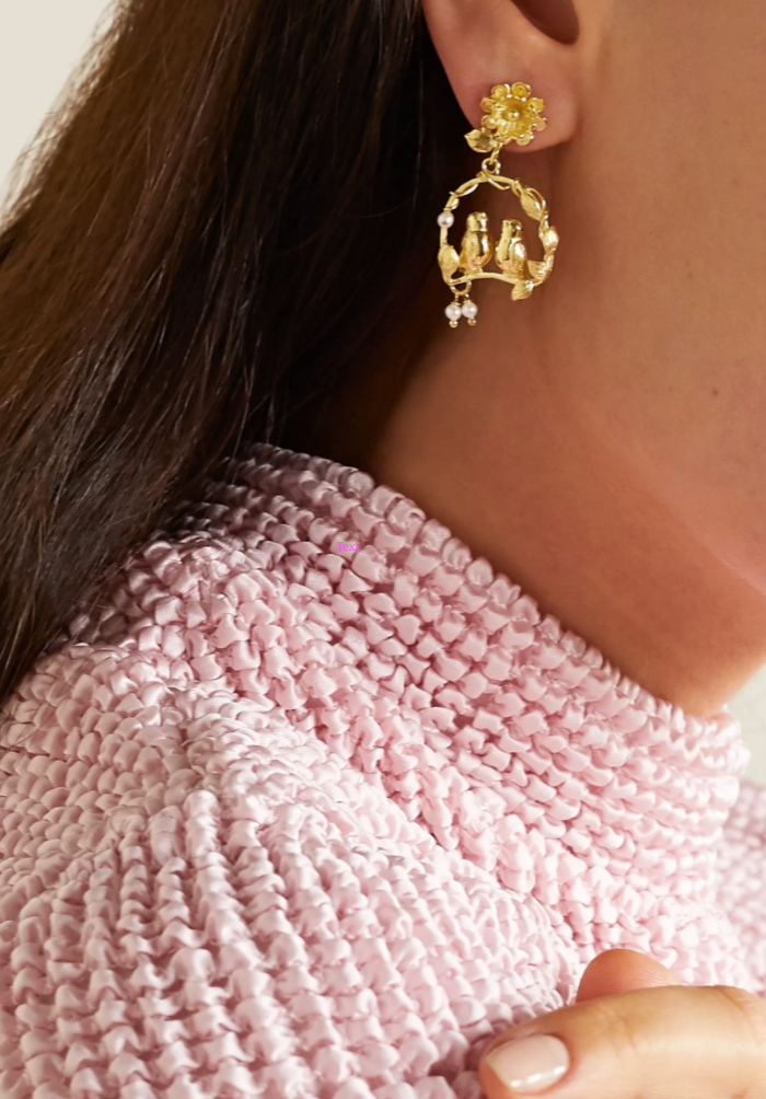 Close-up of Inseparables earring in gold showcasing bird-and-flower motif with dangling pearls on model’s right ear