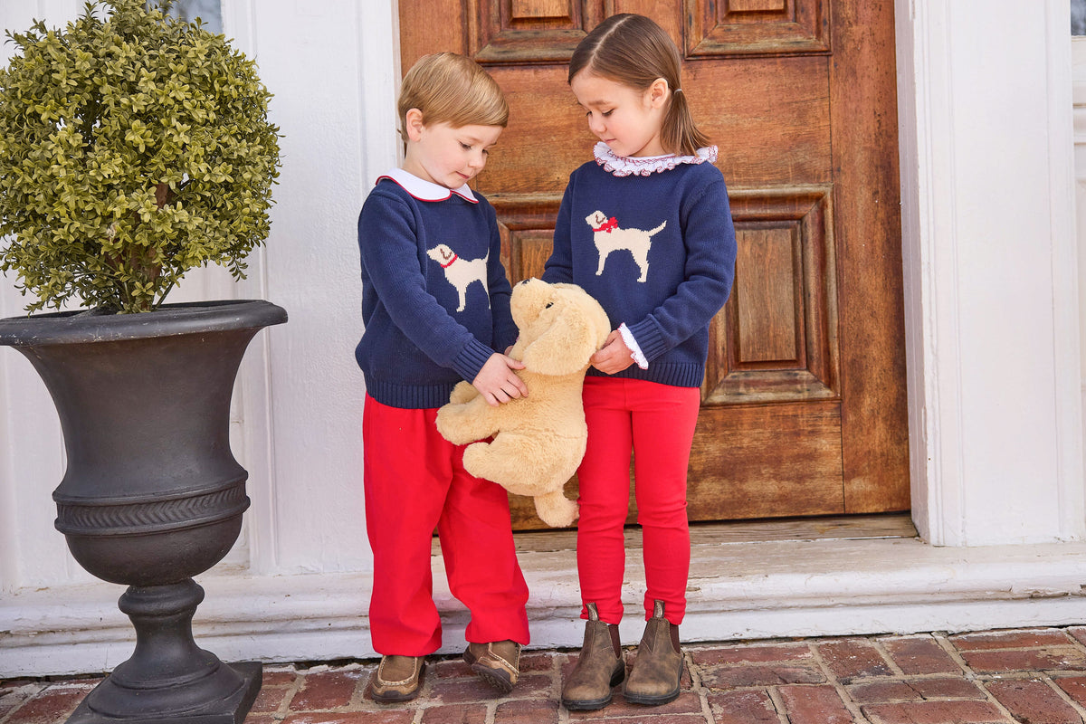 little english classic children's clothing boys navy sweater with cream lab motif, red piped peter pan shirt, and red banded corduroy pant. girls navy sweater with red bow on cream lab motif, smocked madeline blouse in red, and red leggings for fall 