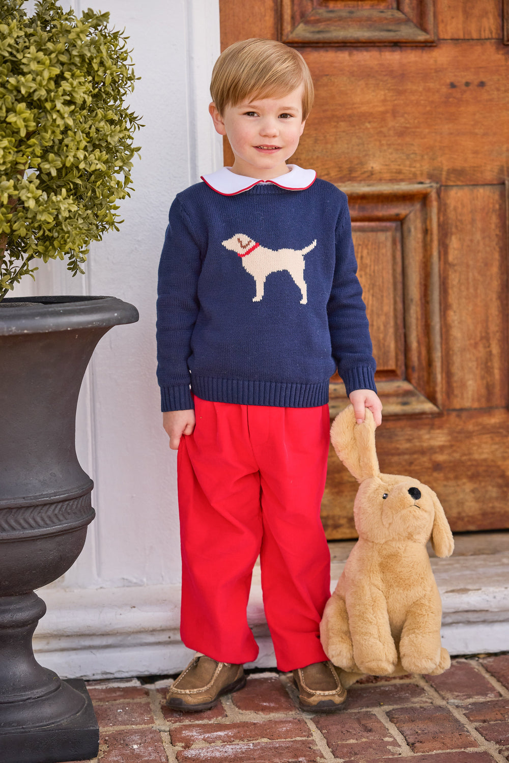 Front view of red corduroy Banded Pant showcasing elastic pull-on waistband and relaxed fit on toddler against wooden door