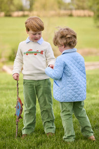 Little English traditional children's clothing.  Boys cream crew neck sweater with fish motif layered over light blue striped polo and paired with watercress green corduroy pants. Little boy wearing light blue quilted jacket with watercress green corduroy pull on pants