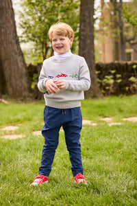 Little English traditional children's clothing.  Grey intarsia sweater with 3 race cars layered over race car print turtleneck and paired with tapered navy sport pants for little boys.