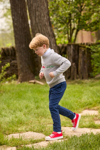 Little English traditional children's clothing.  Grey intarsia sweater with 3 race cars layered over race car print turtleneck and paired with tapered navy sport pants for little boys.