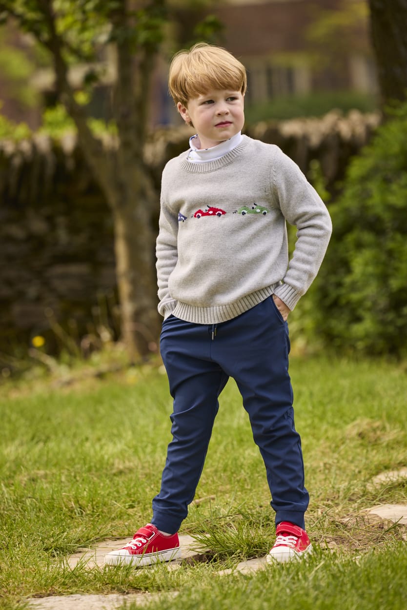 Little English traditional children's clothing.  Grey intarsia sweater with 3 race cars layered over race car print turtleneck and paired with tapered navy sport pants for little boys.