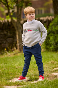 Little English traditional children's clothing.  Grey intarsia sweater with 3 race cars layered over race car print turtleneck and paired with tapered navy sport pants for little boys.