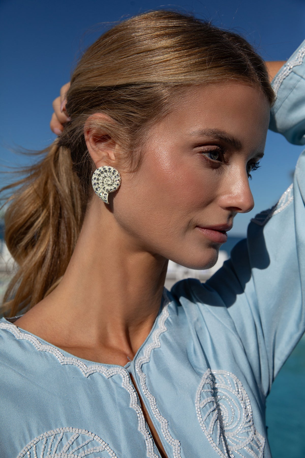 Side view of Isola Sparkle Stud on model showcasing ivory resin nautilus shape with Swarovski crystals and white gold–tone finish