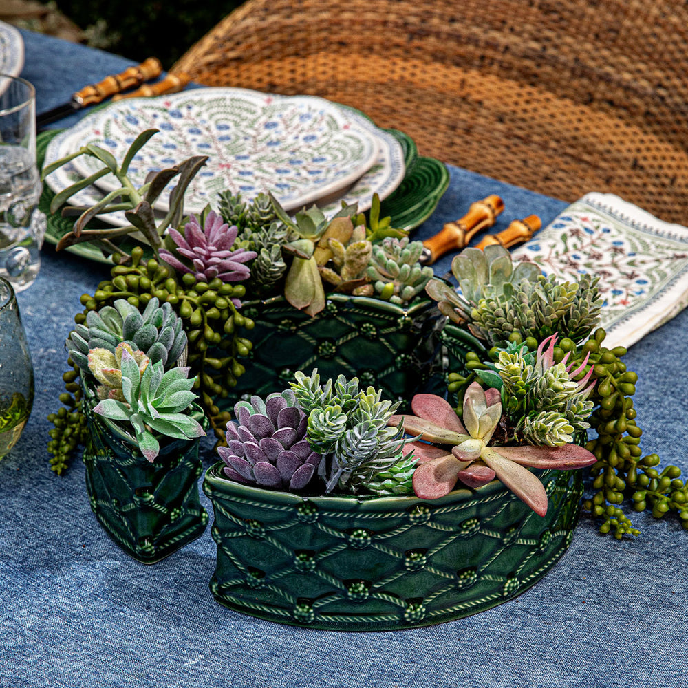 Pair of Berry & Thread Petite Parterre half-circle vases in basil glaze showcasing Berry & Thread lattice detailing filled with succulents on a blue tablecloth