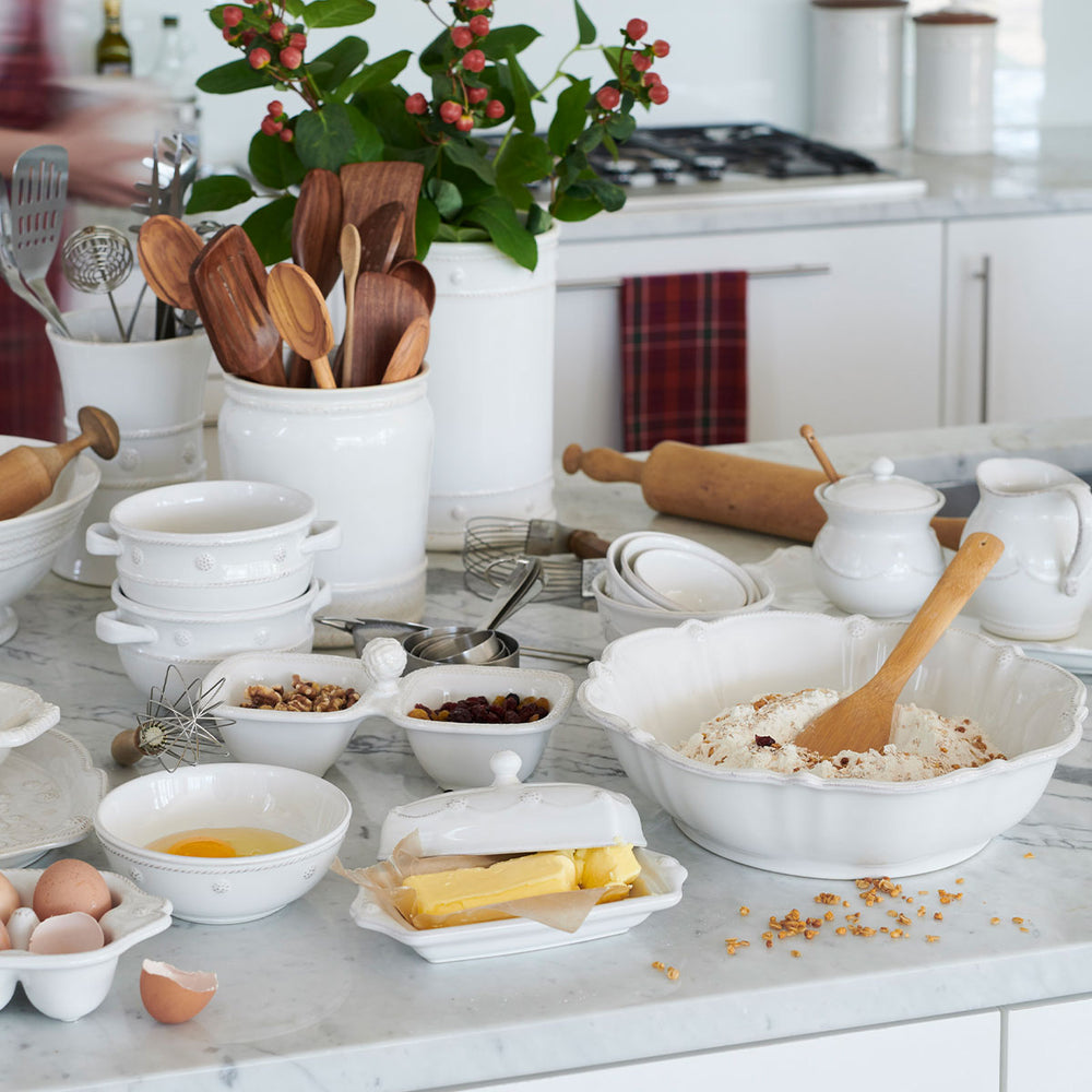 Set of four whitewash Berry & Thread nesting prep bowls arranged on a marble kitchen counter with wooden utensils, eggs, butter, and a rolling pin