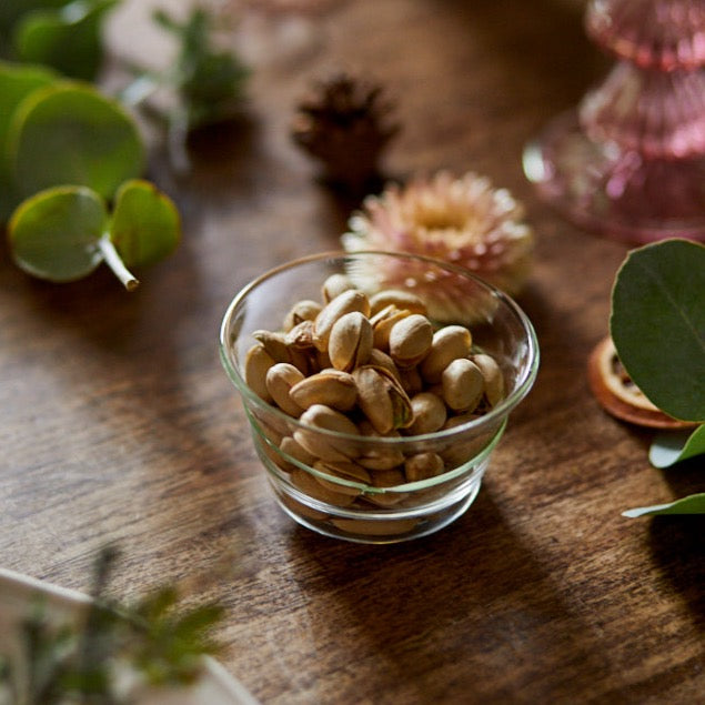 Close-up of Green Circle Bowl showcasing handblown borosilicate glass filled with nuts on a wooden table