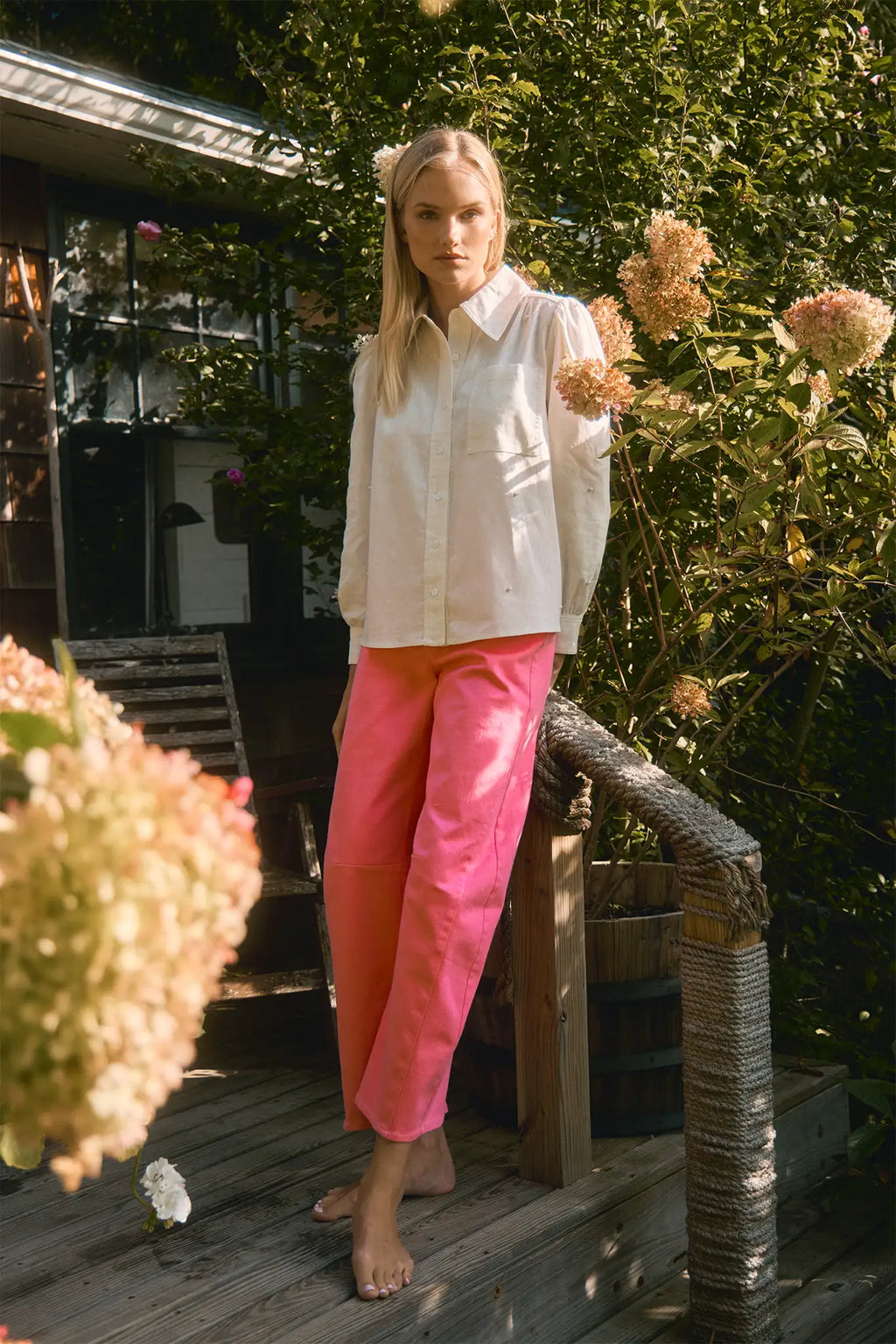White linen long-sleeve collared shirt with roll-tab sleeves and pearl embellishments.