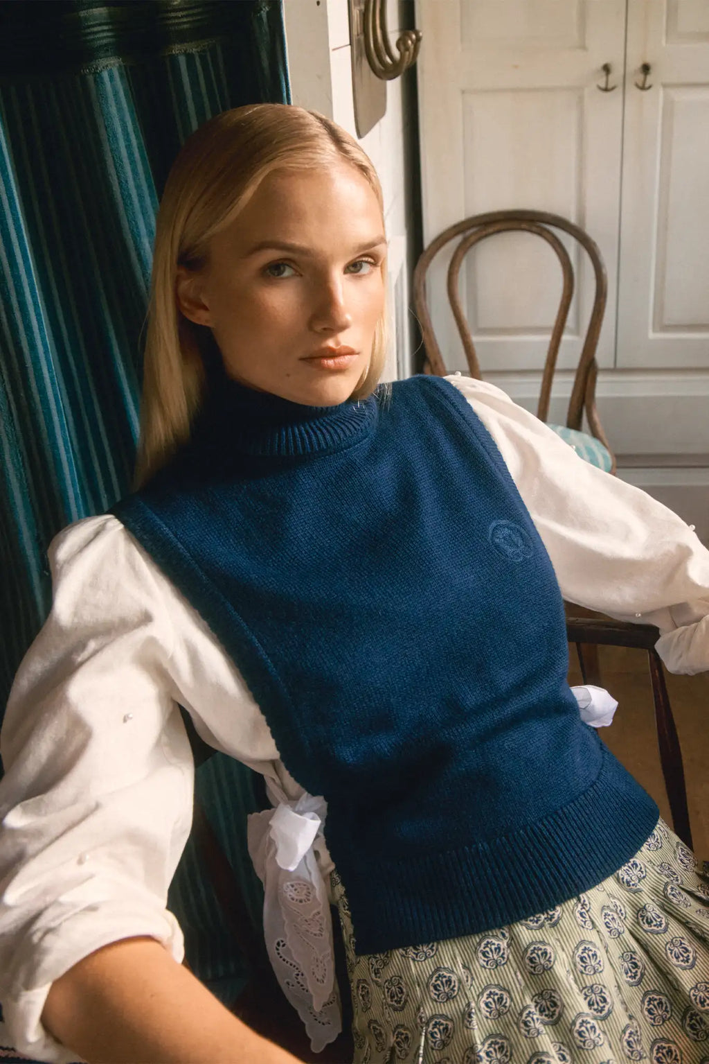 White linen long-sleeve collared shirt with roll-tab sleeves and pearl embellishments.
