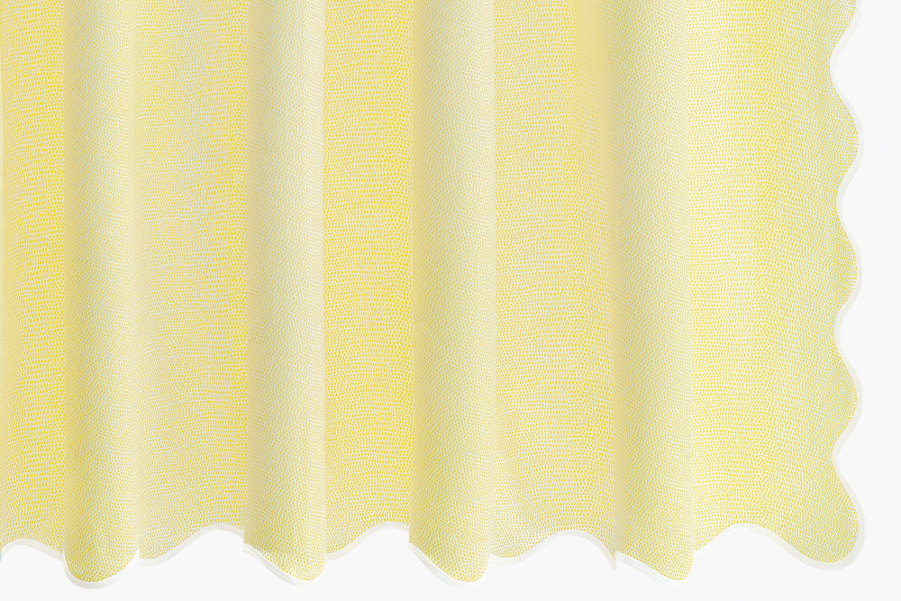 Close-up of Jasper shower curtain showcasing pebbled sateen texture and white scalloped taped edge in lemon on white background