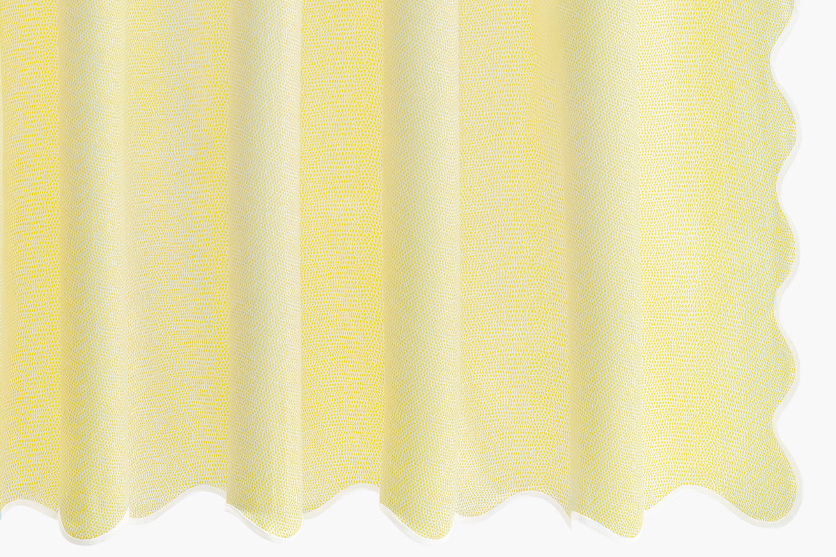 Close-up of Jasper shower curtain showcasing pebbled sateen texture and white scalloped taped edge in lemon on white background