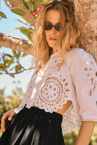 A lace crop top with scalloped lace edges, cutout embroidery, 3/4 length sleeves and shoulder puffs.