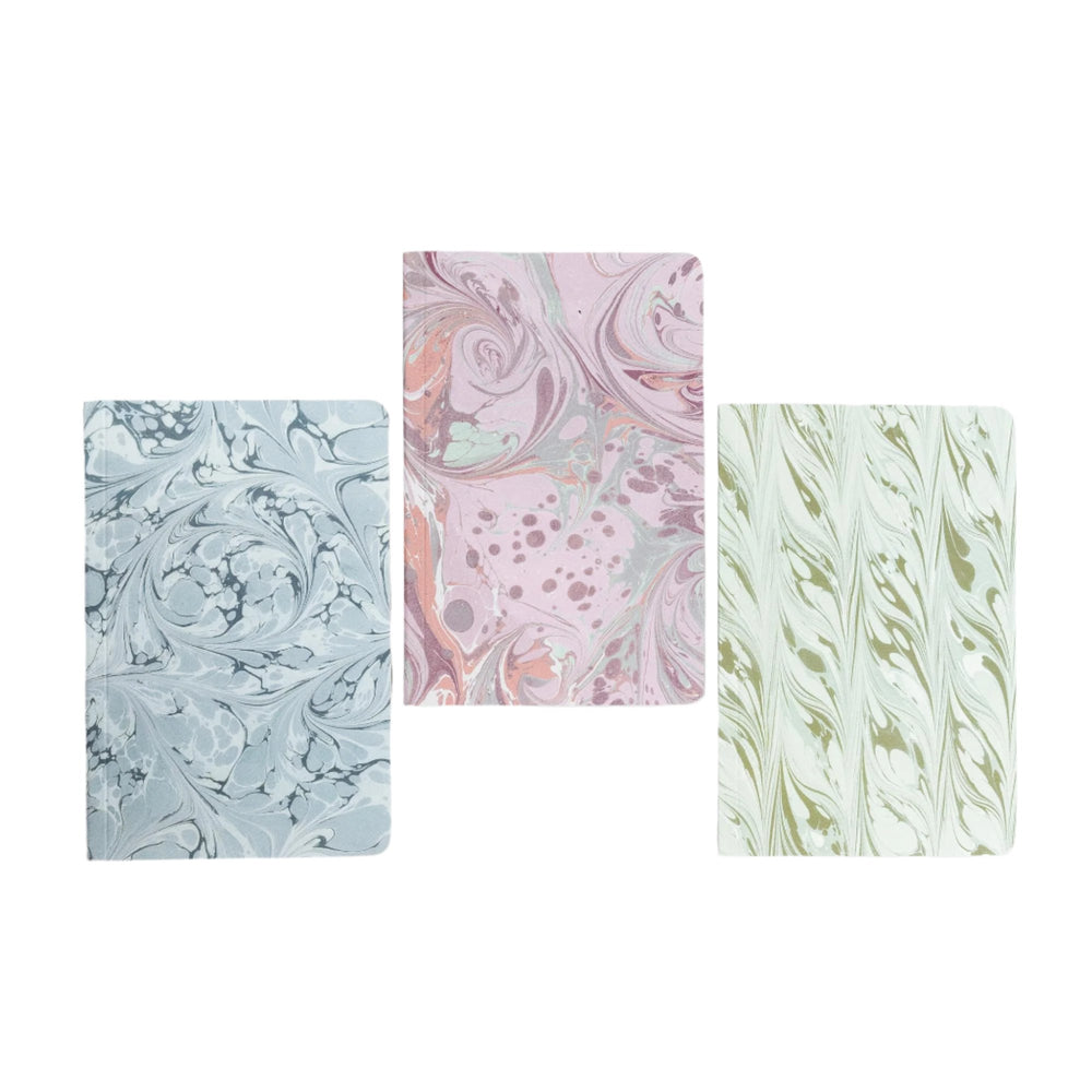 Front view of three pocket journals showcasing blue, pink, and green marble-pattern covers on white background