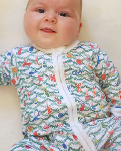Front view of Oh Christmas Tree Zip Baby Onesie showcasing whimsical holiday print and white two way zip on a baby