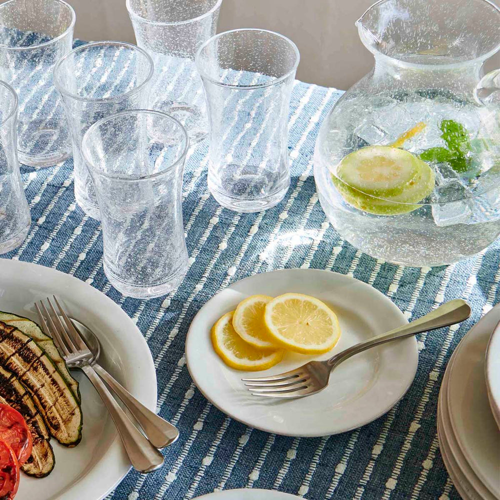 Top view of Puro Side/Cocktail Plate in Whitewash showing textured glaze with lemon slices on blue runner