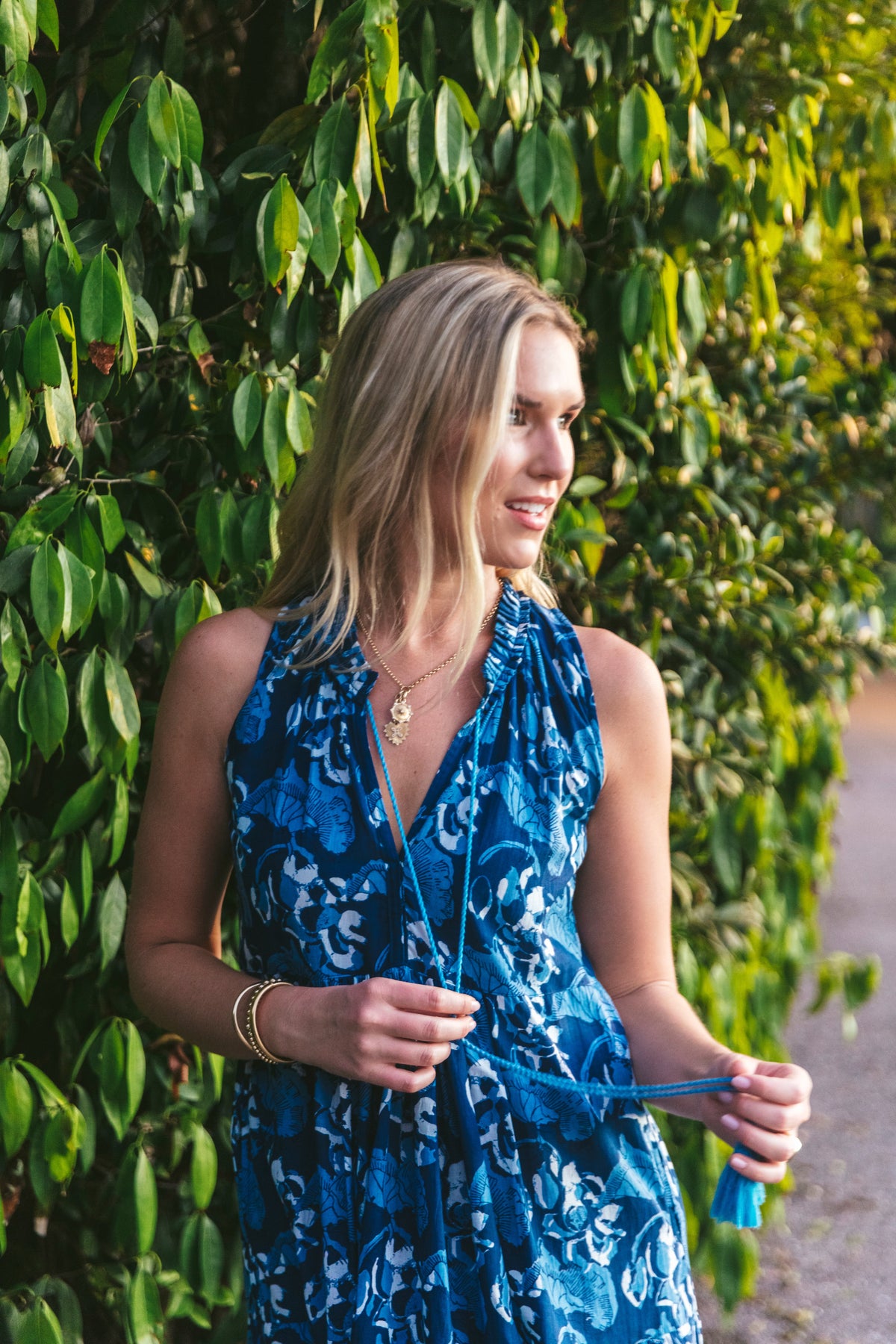 Close view of La Guerite Dress in Independence showcasing blue floral print and gathered waist with leafy background