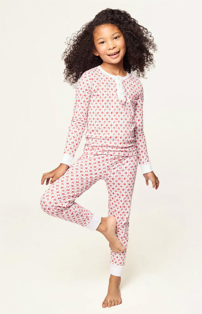 Front view of a child wearing a white Pima snug-fit pajama set with red apple print against a light background