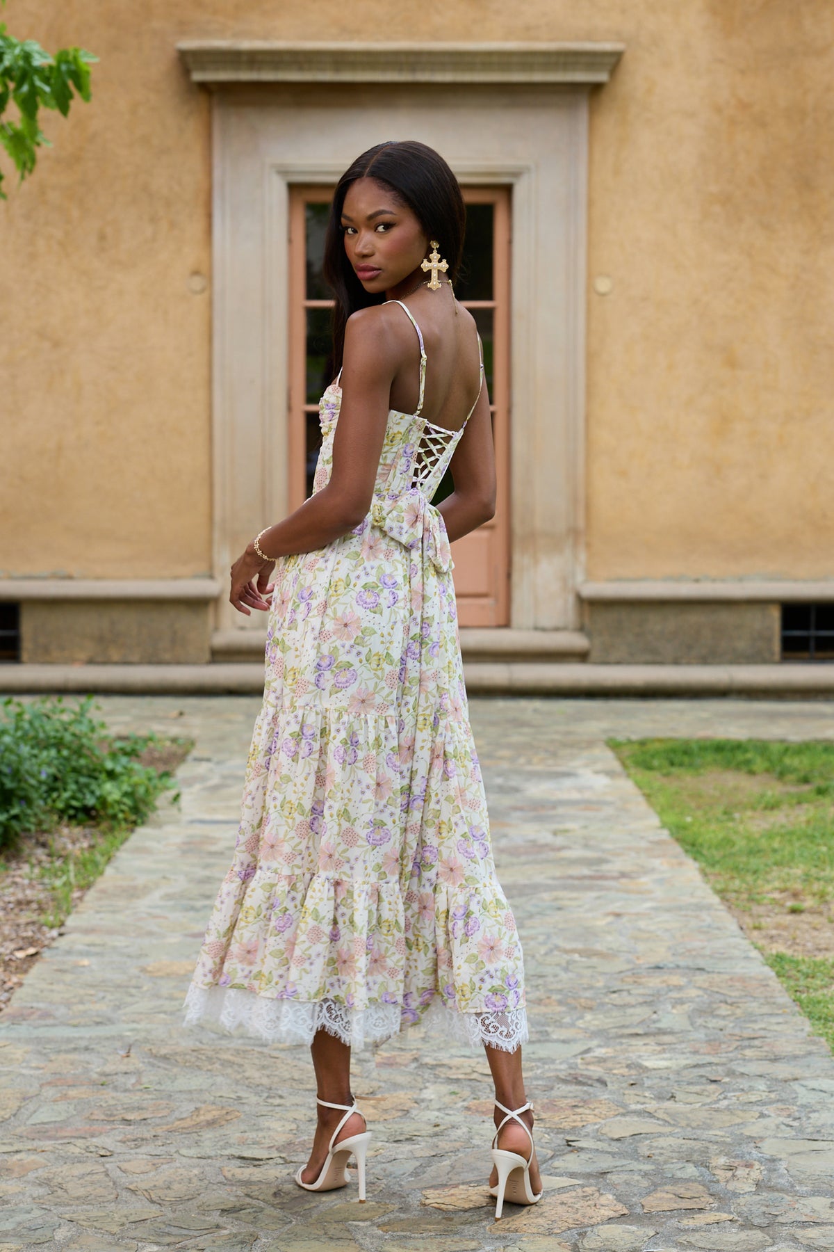 Back view of The Lara Dress in Cordoba Print showcasing its lace-up corset back and tiered floral skirt outdoors